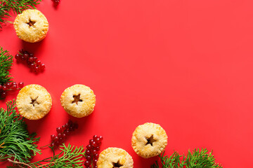 Tasty Christmas mince pies with cranberry and fir branches on red background