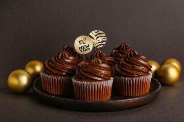 Tasty cupcakes for New Year 2022 celebration on dark background
