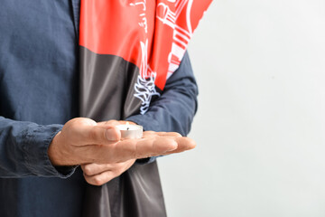 Man with flag of Afghanistan and candle on light background, closeup