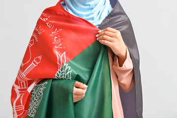 Woman with flag of Afghanistan on light background