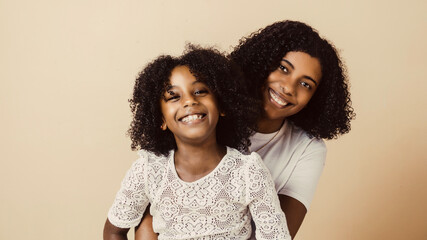 little girl and young black woman together looking at camera. mother and daughters hugging.