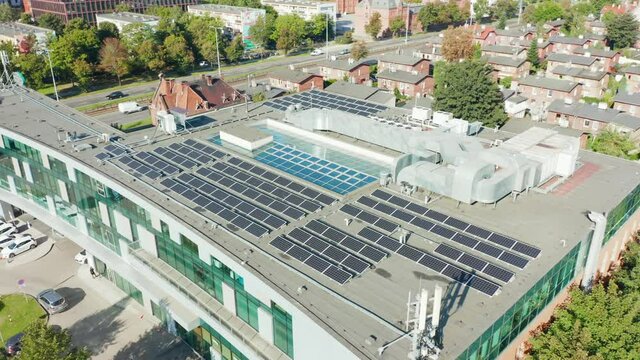 An aerial view of a modern photovoltaic solar array. Rows of solar panels of sustainable energy installed on the flat roof of a commercial building. The concept of ecology.