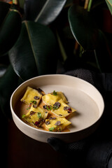 Italian ravioli with truffle sauce and truffle slices on black leather