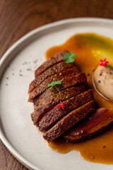 Juicy strip loin steak on wide white plate, directly above view