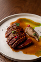 Juicy strip loin steak on wide white plate, directly above view