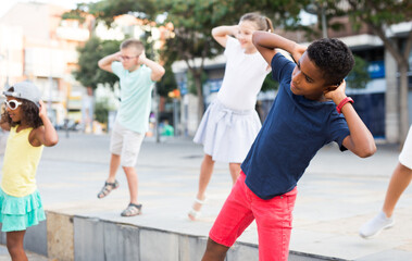 Fototapeta premium Young boys and girls dancing outdoors. They're performing street dance moves and having fun.