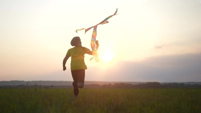 girl run with a kite in the park at sunset. fantasy happy family dream kid concept. child run park play with toy kite. girl kid wants to astronaut pilot. childhood free girl concept fun