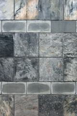 Full frame close-up view of a segment of a building wall with tiles of natural stone