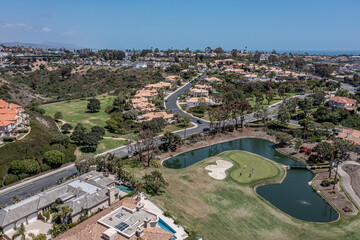 Fototapeta na wymiar Aerial view of a putting green surrounded by water in an upscale neighborhood.