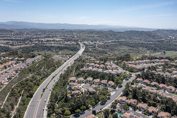 Aerial view of a highway winding through an upscale suburban neighborhood, surrounded by hills