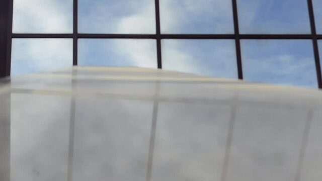 pull focus out of a window looking at a blue sky with white clouds with noticeable depth of field