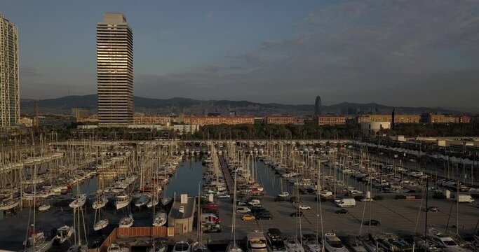 Aerial truck right Port Olimpic and Mapfre tower parking lot cars and boats