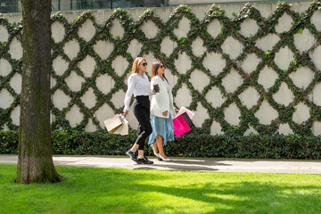 mujeres caminando con bolsas de compras y café mientras platican felices por la calle, compras, turismo, gente feliz.