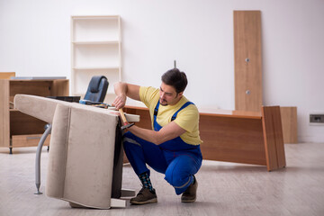 Young male carpenter repairing arm-chair in the office