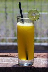 A glass of orange juice with orange sliced on wood table