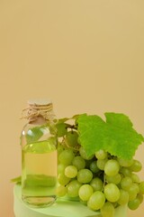 Grape seed oil.bottle and bunch of green grapes on green podium on a beige background. Natural Bio Grape Seed Oil. 