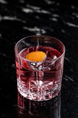 Luxurious photo of bitter pink cocktail with grapefruit, soft light, reflections on a black bar counter