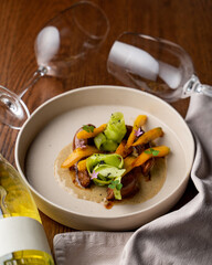 Braised pear dessert with honey sauce in a posh restaurant, linen cloth and bottle of wine aside