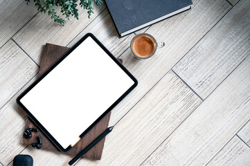 Top view blank screen tablet, gadget, book and coffee cup on wooden table with copy space.