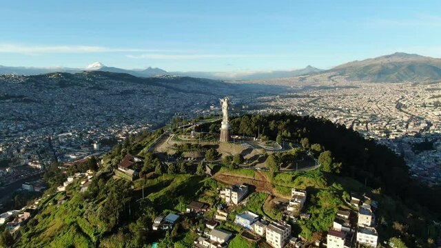 Aerial: Virgin of El Panecillo at sunrise with Quito city backdrop, Ecuador
