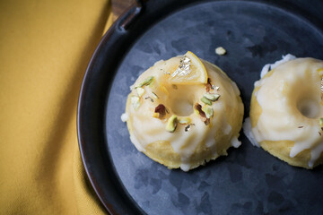 Lemon cake with sugar sweet icing on yellow and black background. Cake with citrus, poppy, traditional american cuisine in dark tone
