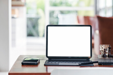 White screen tablet with magic keyboard and smartphone on the table in living room.