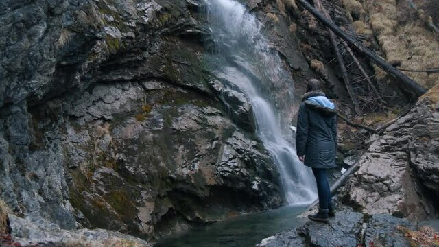 Girl enjoying the untouched nature in front of a waterfall in Switzerland.