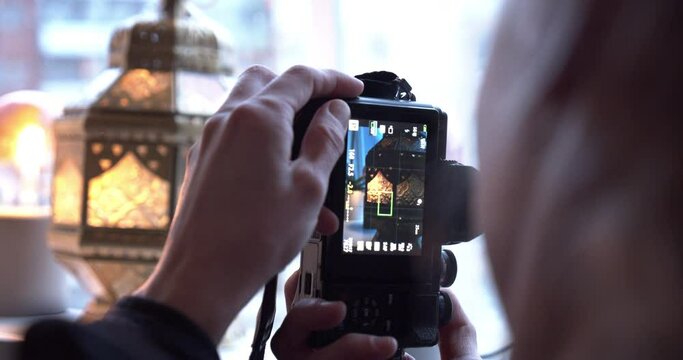 Caucasian woman takes photos of lantern indoors, close up shot