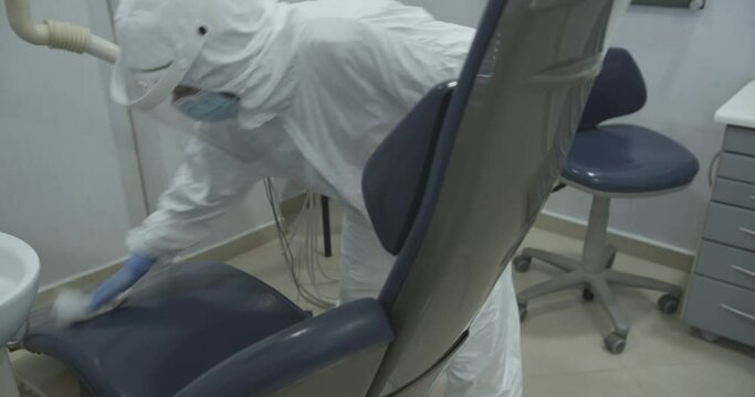 A dentist wiping down a chair getting ready for a patient, static shot