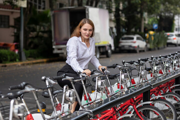 Mujer tomando una bicicleta de aplicacion para trasladarse en la ciudad usando transporte...