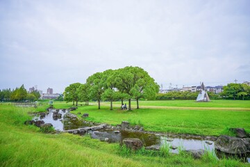 Fototapeta na wymiar 大きな芝生広場と小川がある公園の情景＠大阪