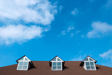 Three windows on a roof of house with a beautiful sky and cloud background