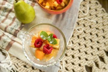 Fruit salad of various berries and fruits pieces served for breakfast on wooden background, healthy eating, wellbeing. 