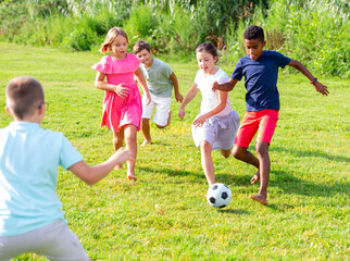 Obraz premium Group of barefoot kids playing football on grass. They're kicking ball and having fun.
