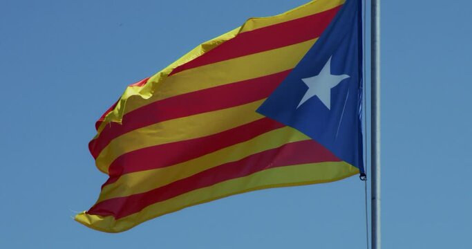 Catalunya flag flattering in slow motion against clean blue sky