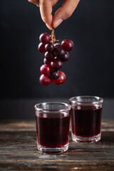 Red grape juice in a glass with hand holding grape, Healthy drink