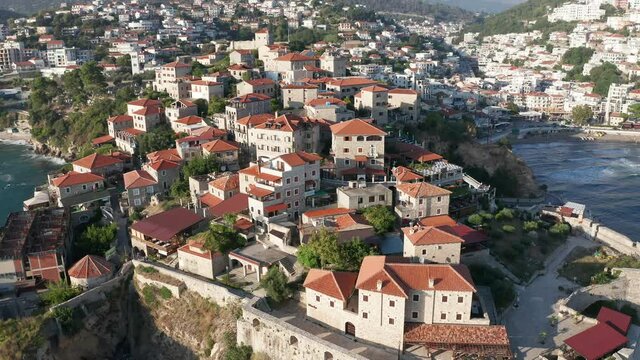 Ulcinj Montenegro old town on the Mediterranean sea coast is popular tourist destination, medieval stone houses with red roofs built on rocky promontory. Drone aerial view of the sunny cityscape.