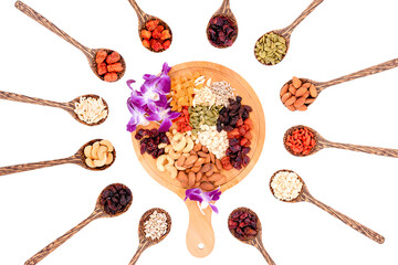 Top view group of whole grains and dried fruits 12 kinds with a beautiful orchid on a wooden plate and wooden spoons isolated on white background.