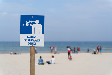 Sign on the beach of the Baltic Sea near Kołobrzeg with the inscription Order to observe children (Nakaz Obserwacji Dzieci) - obrazy, fototapety, plakaty