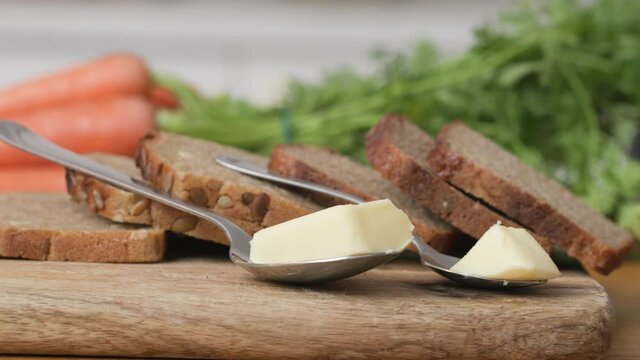 Wooden cutting board with slices of wholemeal bread and two servings of butter. Healthy choice for weight watchers. Slide shot right 4k