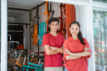 woman and man bicycle shop owner with folded arms standing in front of the shop