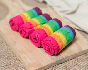 Obraz na płótnie Canvas Sponge rolls consist of several colors forming a rainbow formation. Start your morning with a piece of sponge and warm tea. Sponge with a sweet taste and soft texture. Focus blur. Rainbow cake mockup.