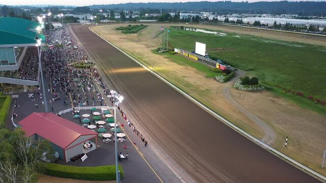 Cinematic 4K aerial drone footage of a horse race at Emerald Downs, a thoroughbred racetrack with a green grandstand in Auburn, Washington, near Highway 167