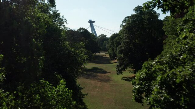 Aerial shot of SNP UFO bridge with trees in foreground - Landmark in Bratislava, capital of Slovakia - summer sunny day