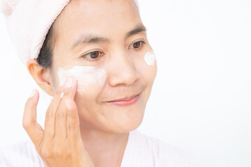 Woman applying lotion skin serum cream on face with smile after shower. Moisturizer skin care for moisturized reduce wrinkles and protection UV A, B. cosmetic for beauty and good health concept.