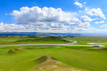 Bayinbuluke grassland natural scenery in Xinjiang,China.The winding river is on the green grassland.Panoramic view.