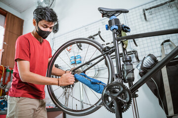 a mechanic in mask working tighten the bicycle axle with a wrench