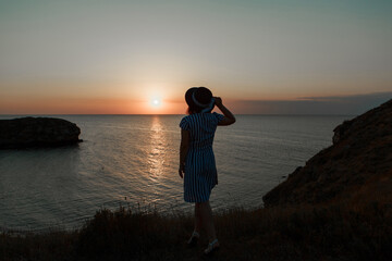 Fototapeta premium a woman on a rock looking into the distance against the sea