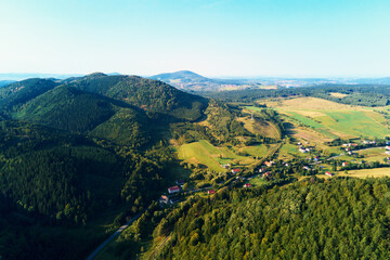 Obraz premium Village near mountain and agricultural fields at sunset. Nature landscapem aerial view