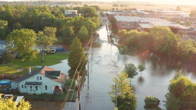 Flood river stream covers streets and roads in small town America, USA. Aerial drone revealing shot at golden hour morning sunrise.